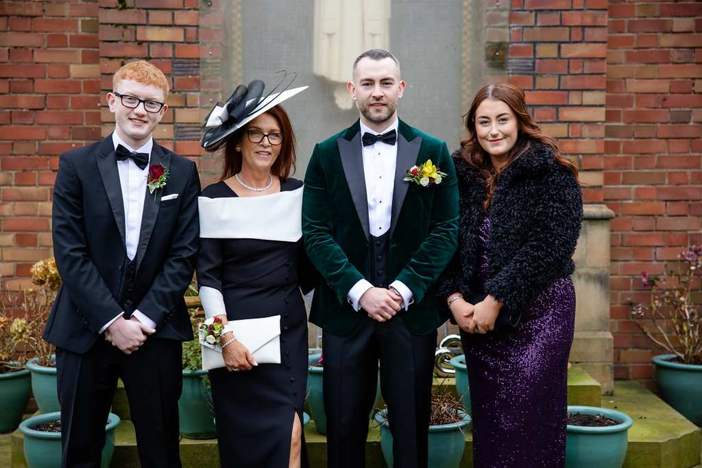 Four people dressed formally, standing in front of a brick building and potted plants, posing for a group photo. Copyright Somerside Photography Ltd // www.somersidephotography.com