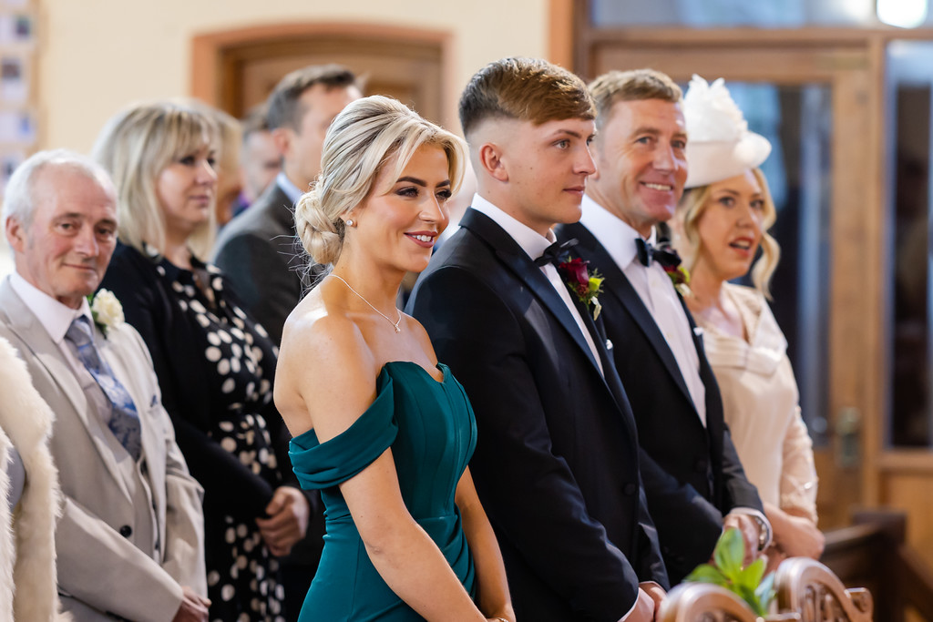 A group of well-dressed people, including a woman in a green dress and a man in a dinner jacket, stand together indoors, likely attending a formal event or ceremony. Copyright Somerside Photography Ltd // www.somersidephotography.com