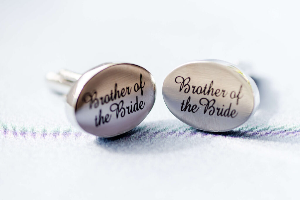 Two silver cufflinks engraved with the words "Brother of the Bride" displayed on a light surface. Copyright Somerside Photography Ltd // www.somersidephotography.com